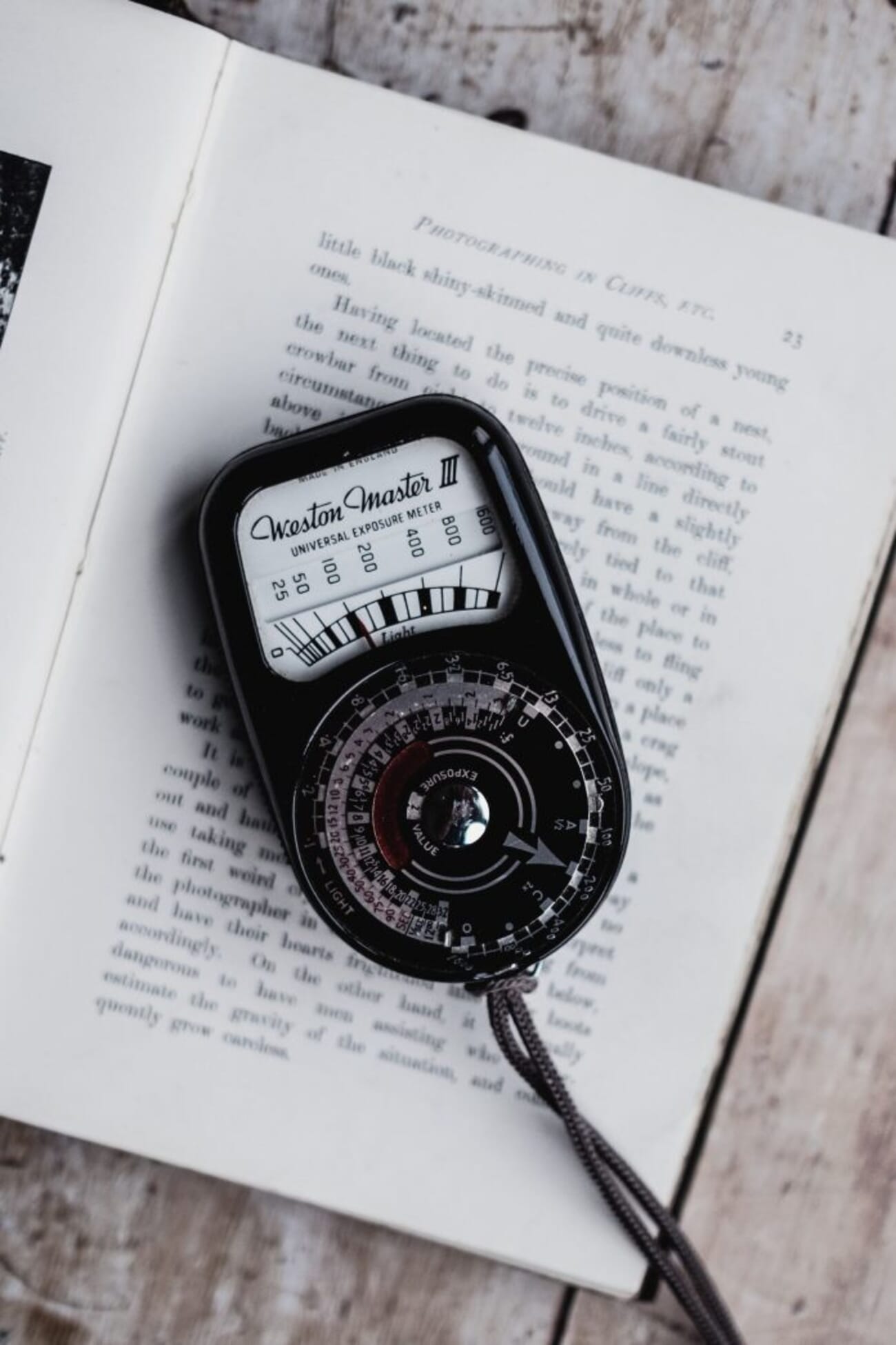 Analog handheld light meter resting on a book