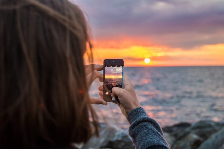 Person photographing the sunset with a smartphone