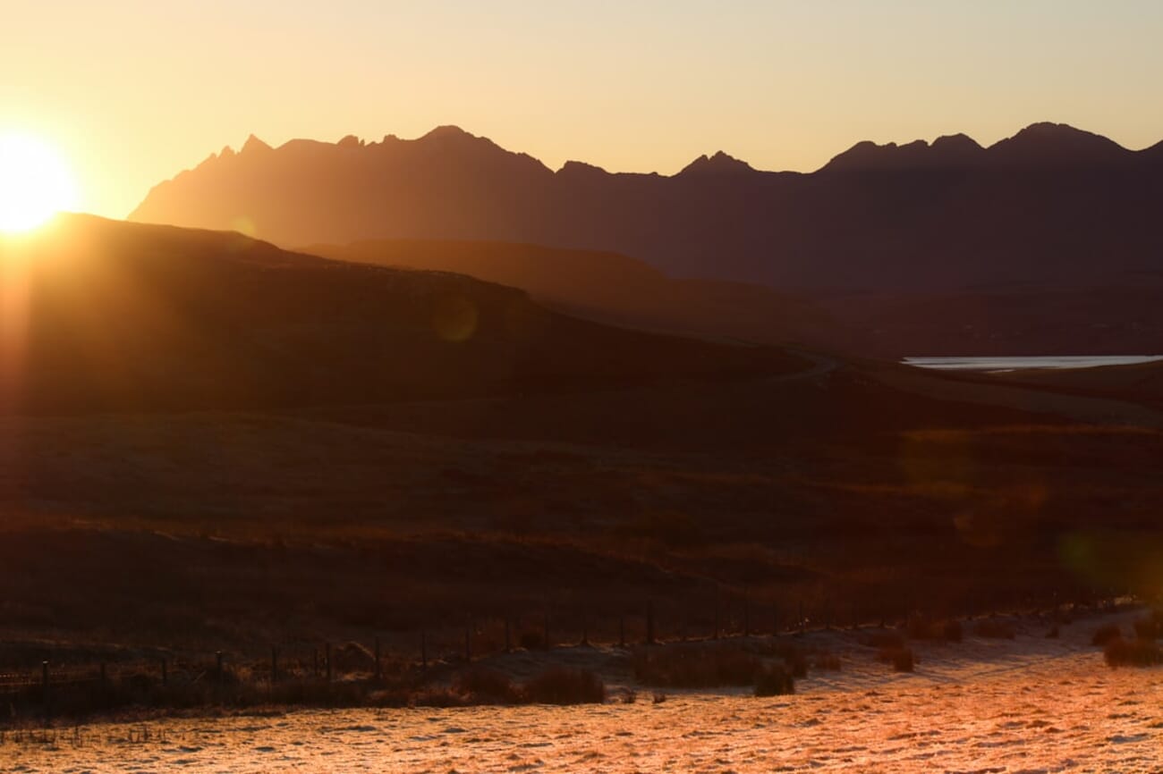 Dramatic sunset over a rugged mountain range reflected in a lake — fine art landscape photography requires physical presence and patience AI cannot replicate