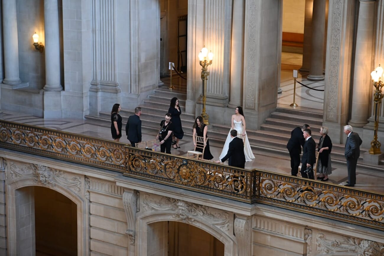 Wedding party posing on a balcony inside a grand building — event photography requires physical presence AI cannot replicate