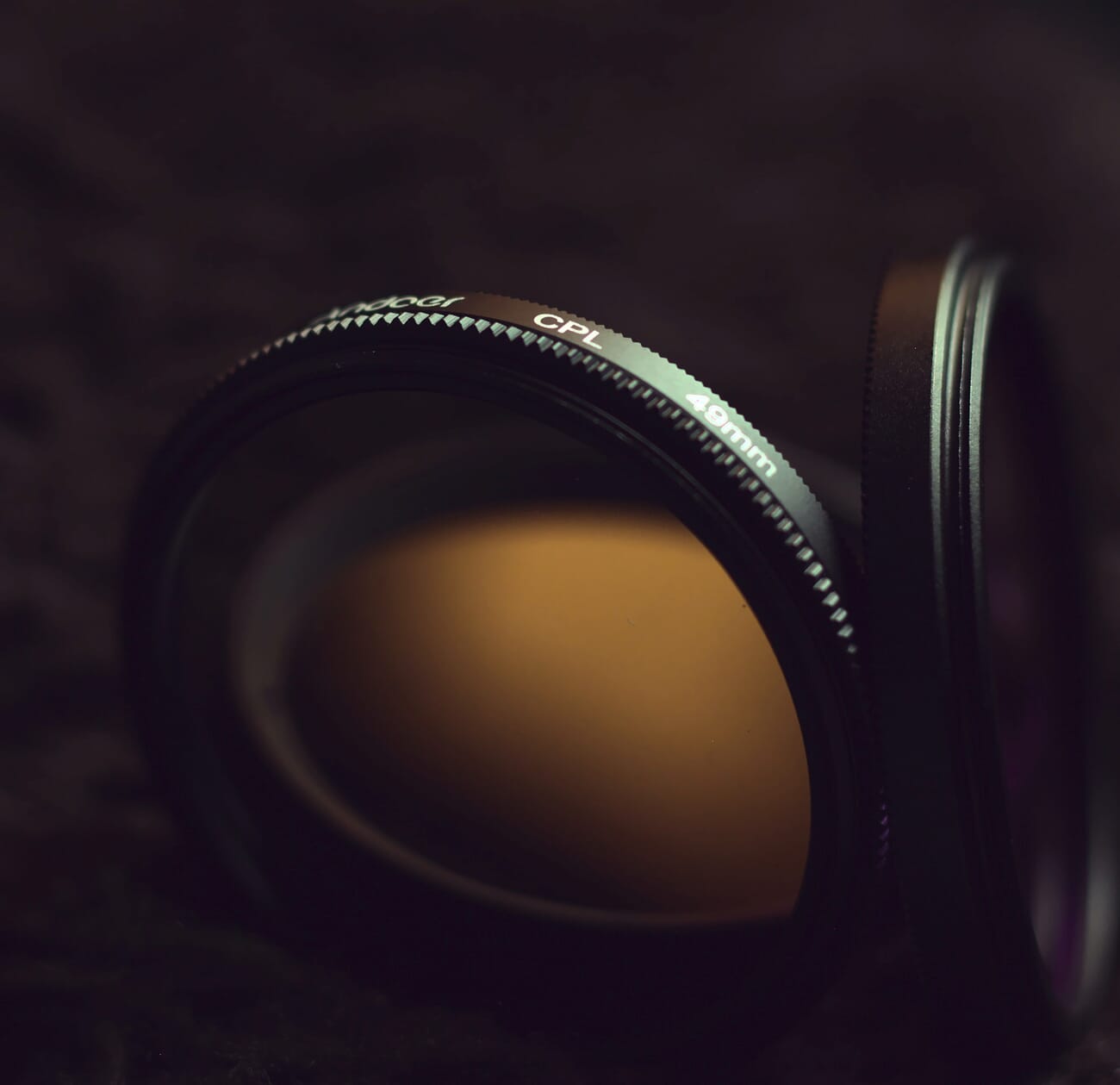 Close-up of two camera filters in dim lighting on a black background.
