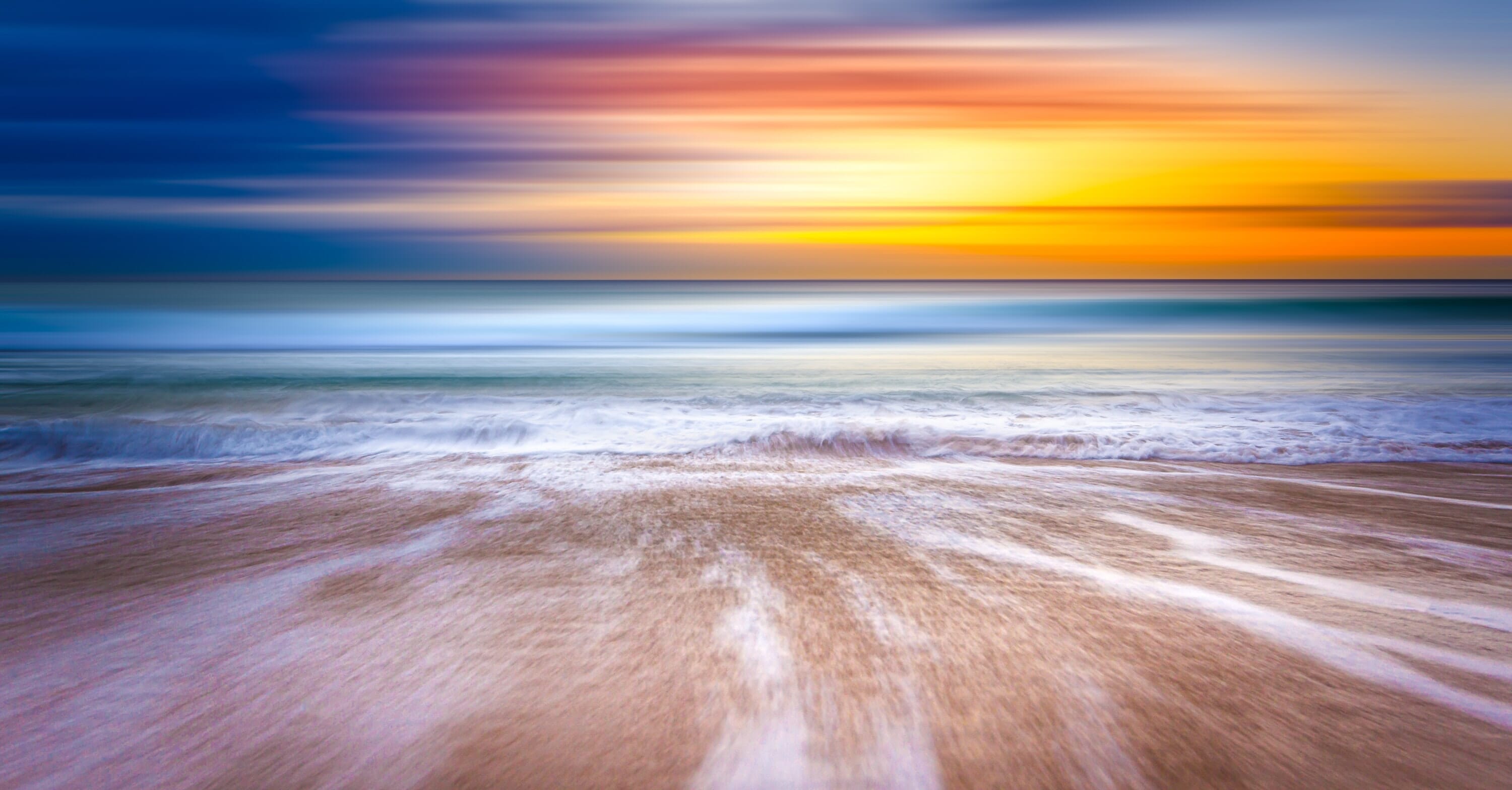Beach sunset with streaky clouds and motion-blurred waves.