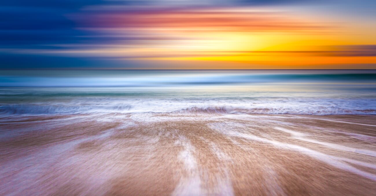 Beach sunset with streaky clouds and motion-blurred waves.