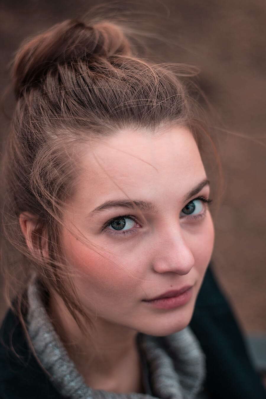 Woman with blue eyes and brown hair looking up at an angle.