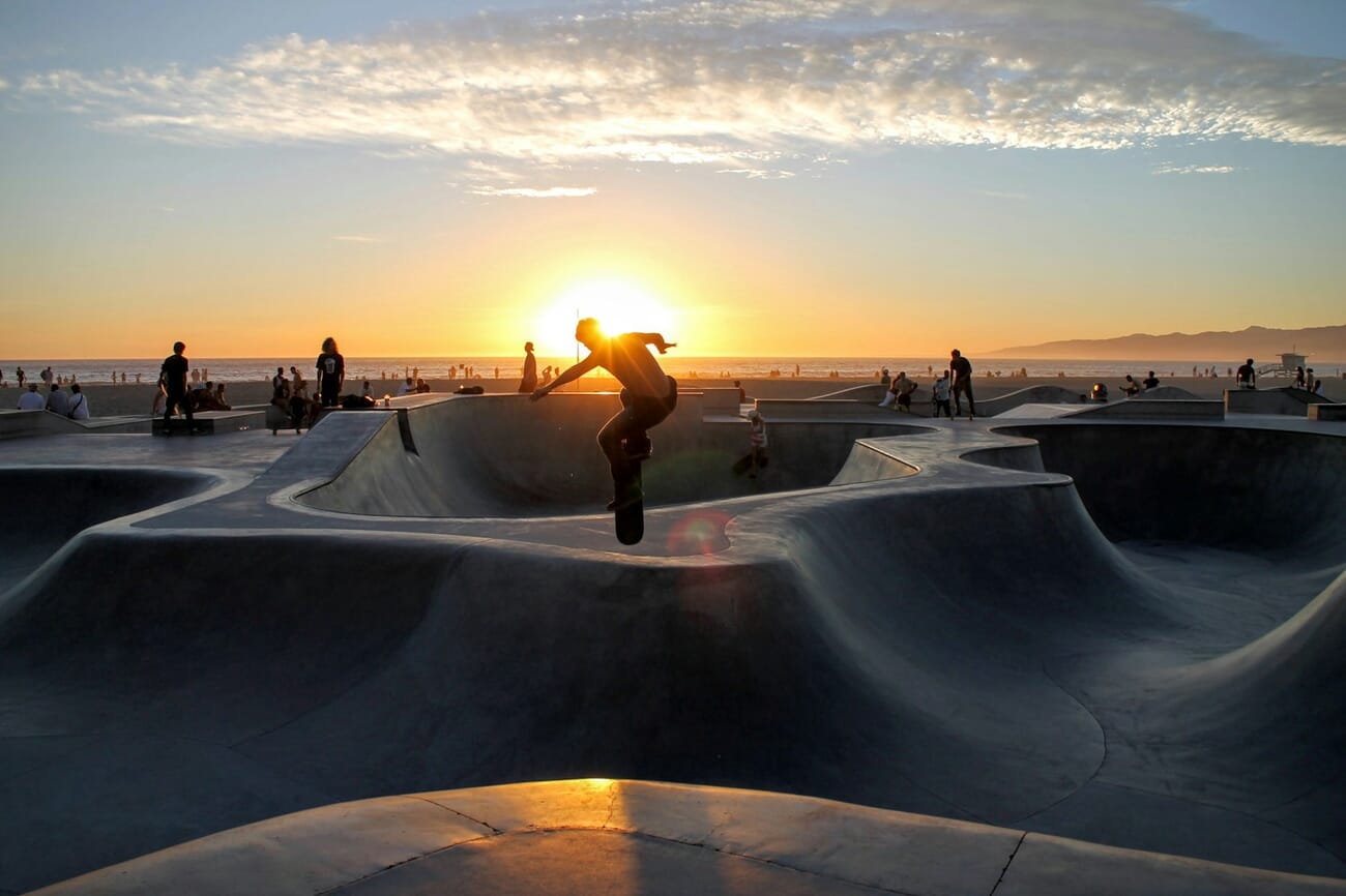 Skateboarder performing a mid-air trick at sunset, frozen in motion with fast shutter speed