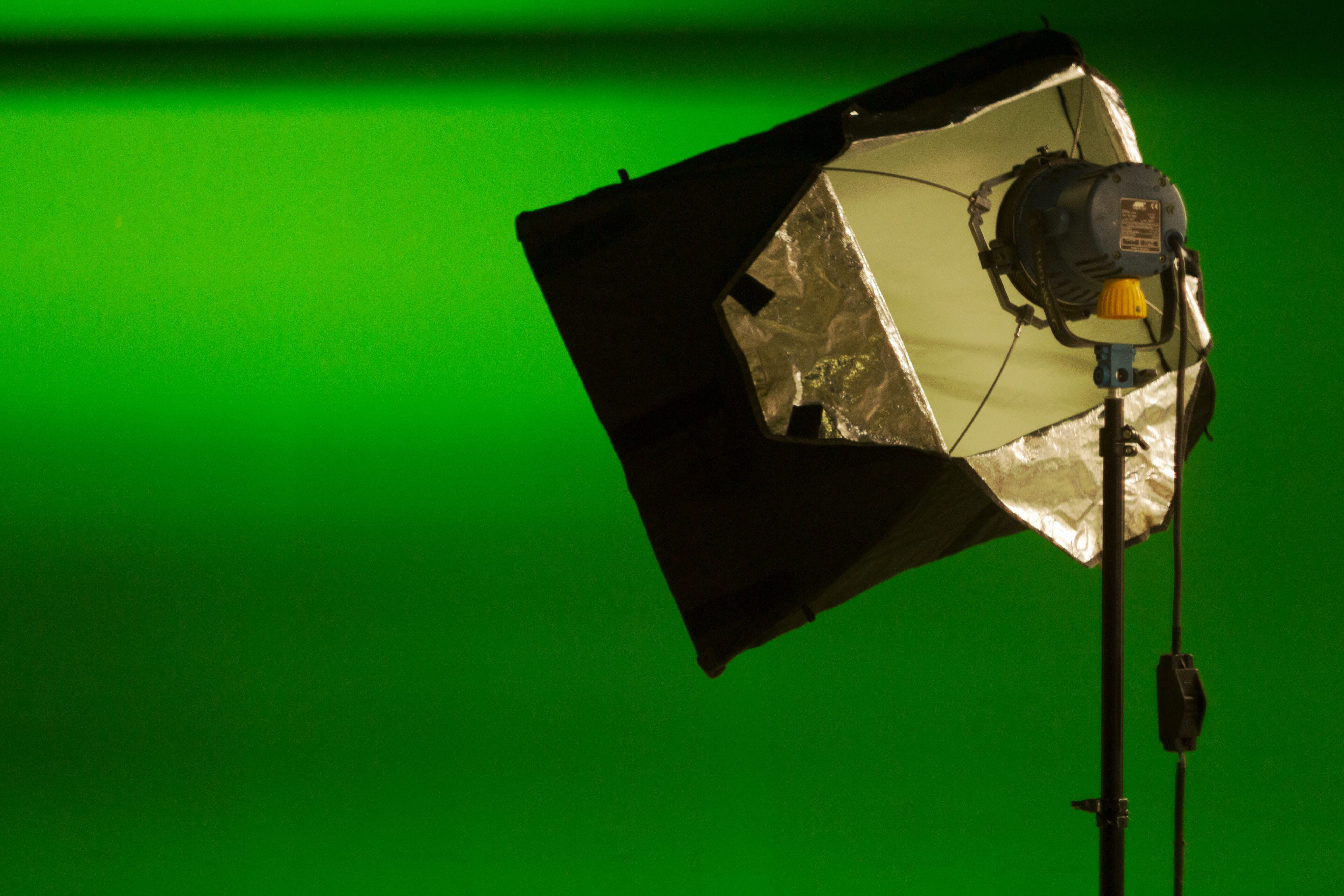 A studio strobe with a softbox modifier facing a green background.