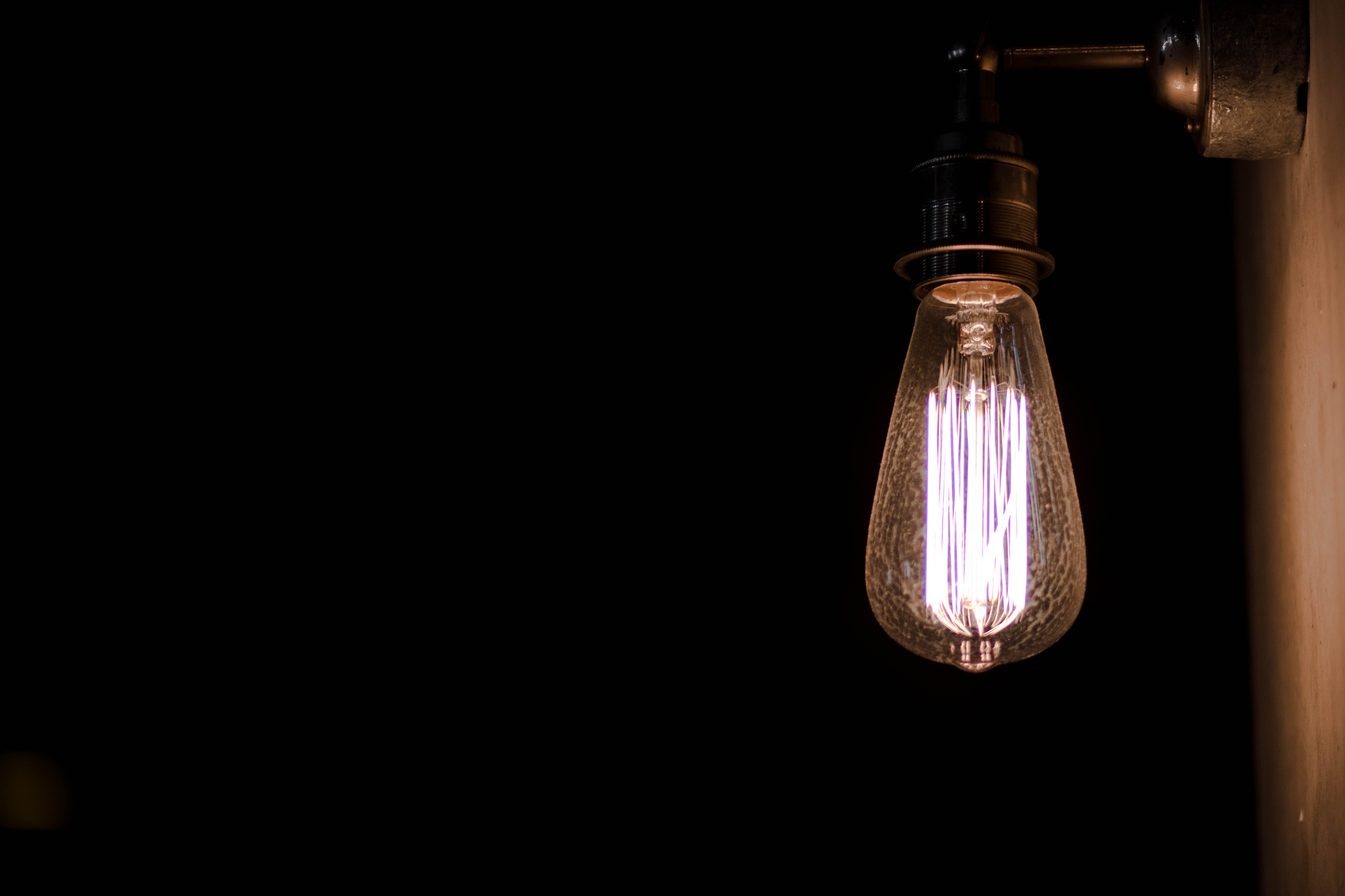 A tungsten lightbulb with bright filaments surrounded by darkness.