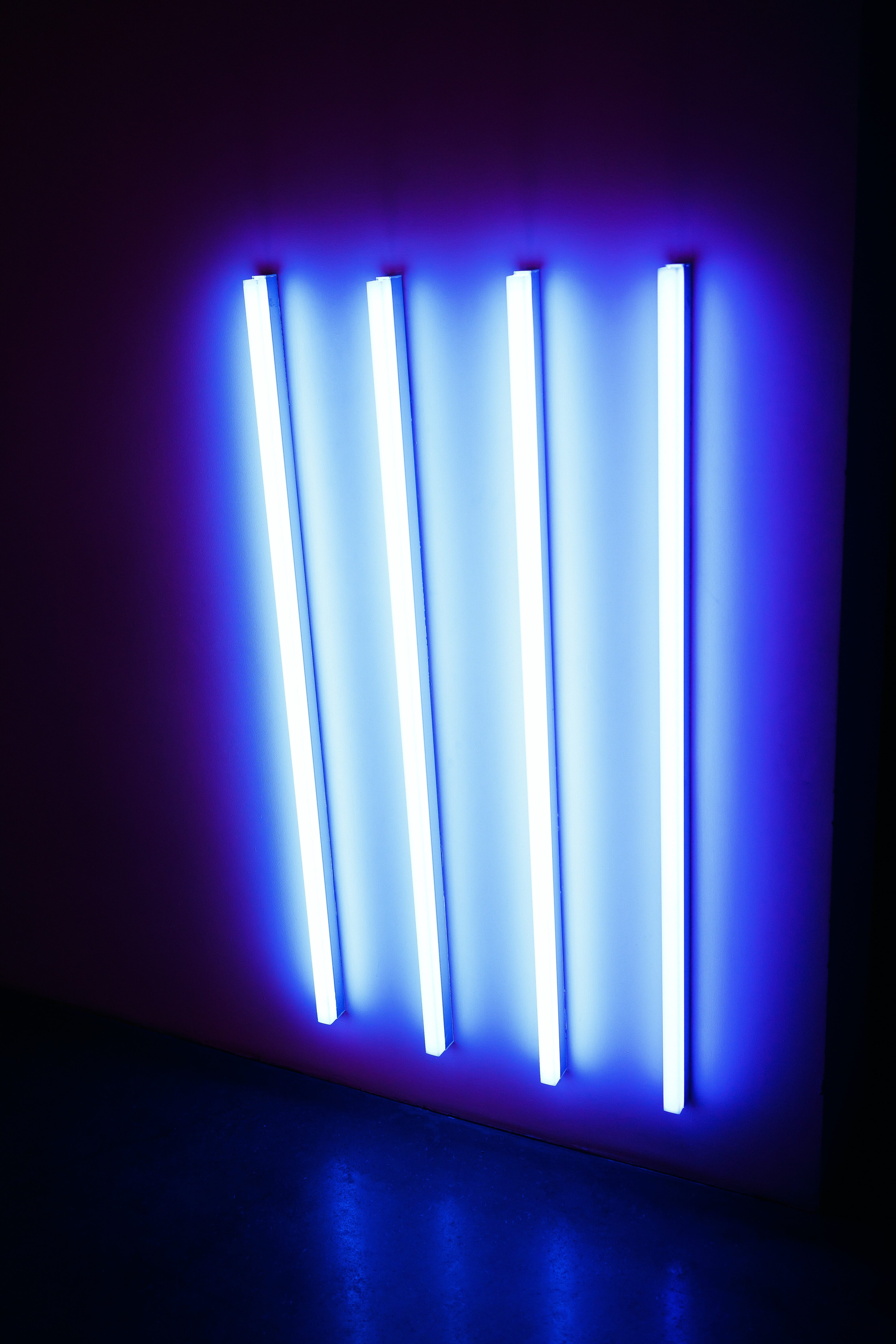 Four fluorescent lights attached to the wall and emitting blue light.