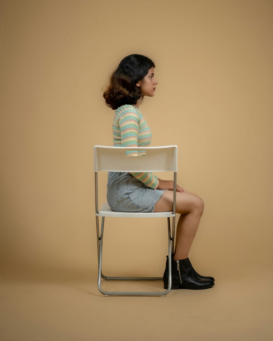 Woman sitting on a chair in a stylish outfit with legs crossed showing proper chair posing technique