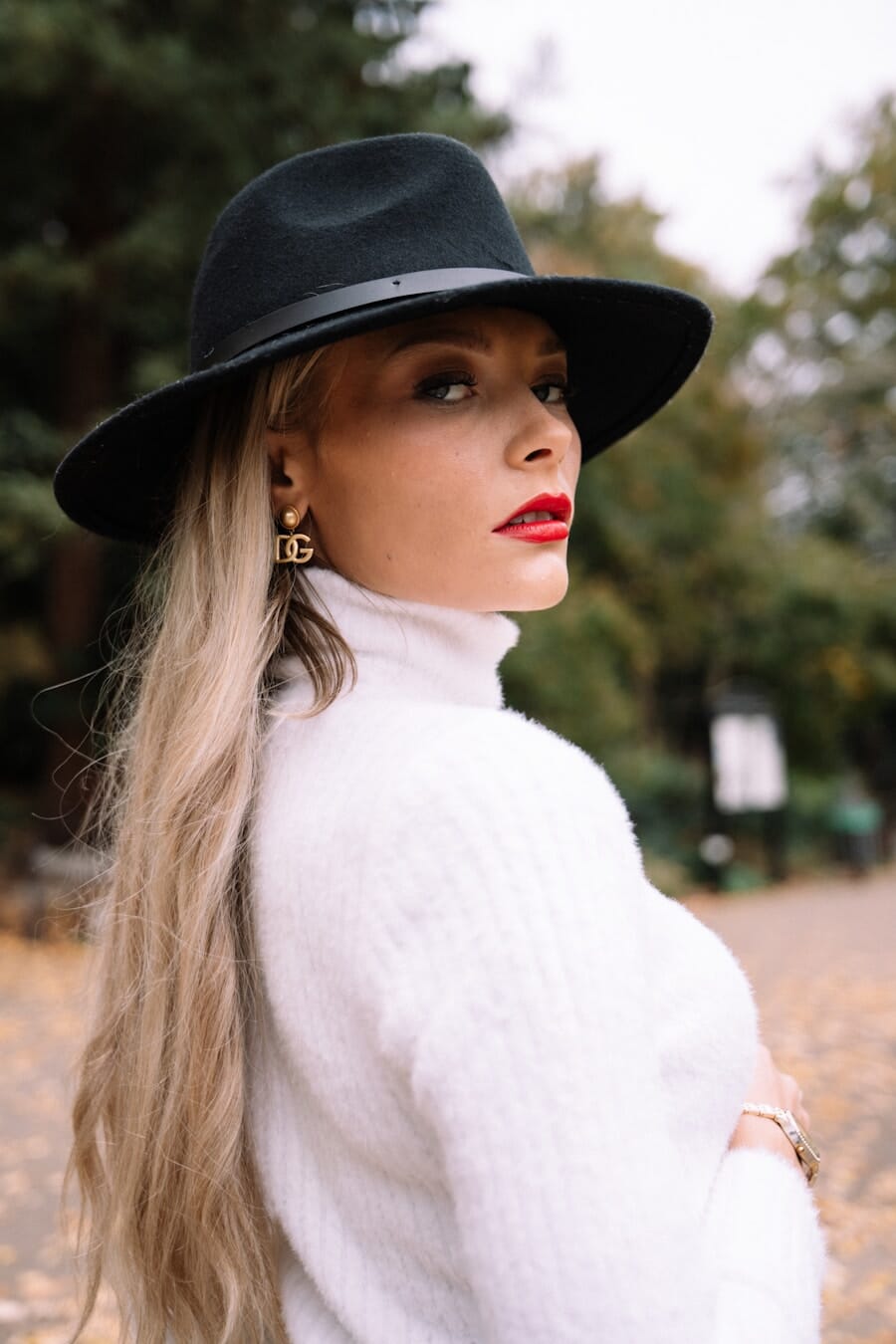 Woman wearing a black hat and white turtleneck looking back over her shoulder creating a mysterious alluring pose