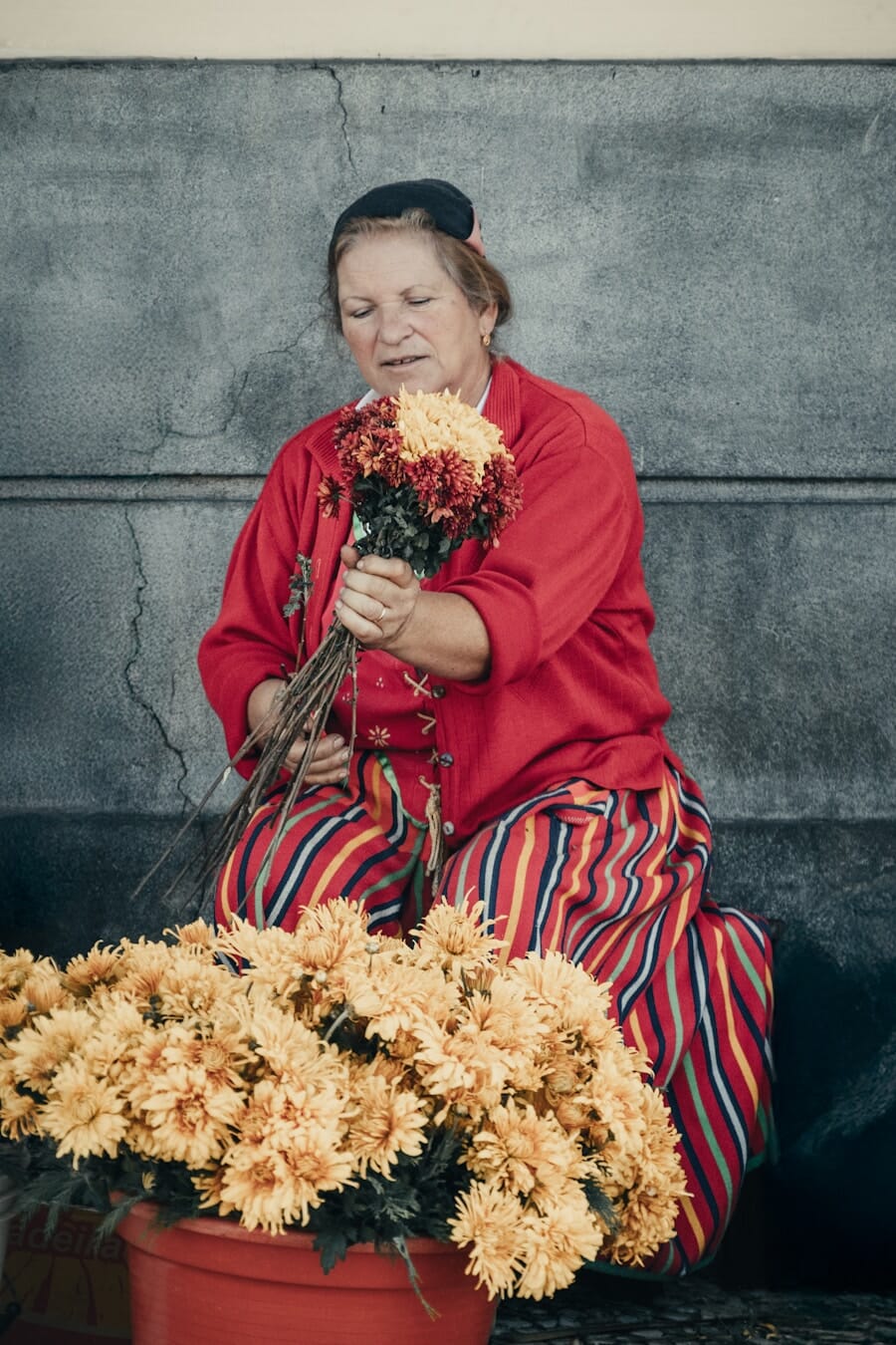 Woman sitting on the ground holding a bunch of flowers as a posing prop