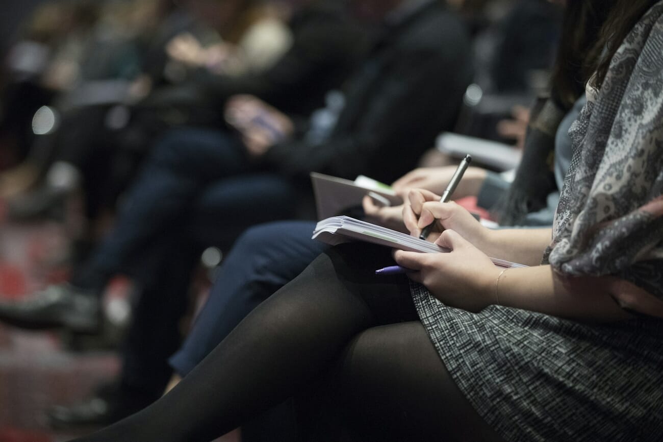 Conference audience taking notes during a keynote presentation
