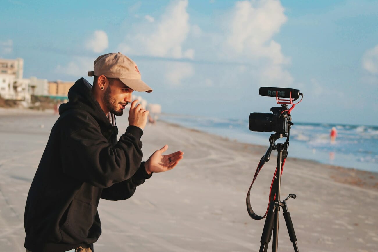 A creator filming themselves with a camera mounted on a tripod, using the rear screen