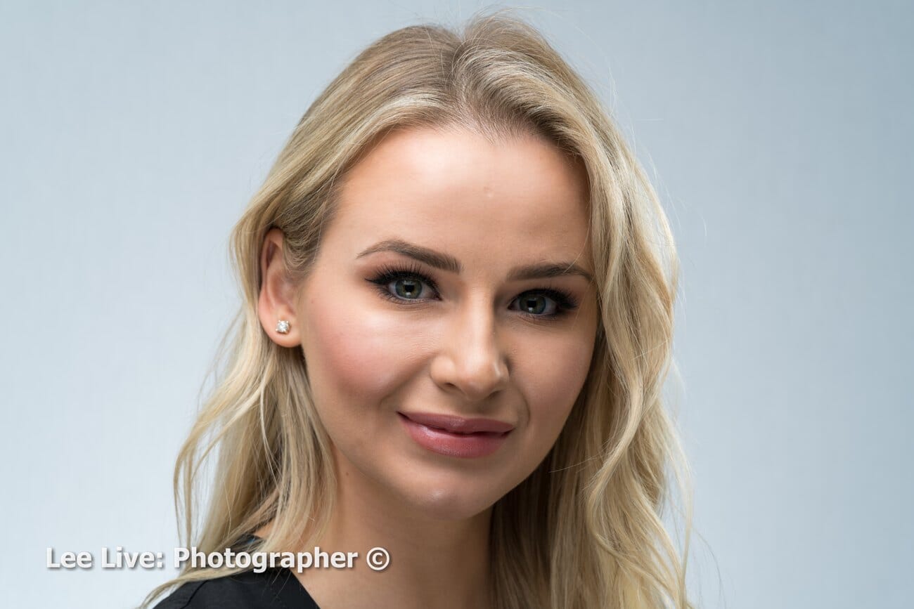 Soft-lit studio headshot of a woman with a smooth, blurred background, shot at 85mm