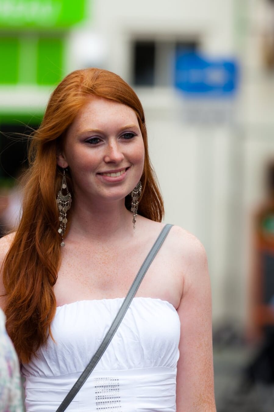 Red-haired woman photographed on an urban street with a compressed, blurred background, shot at 200mm