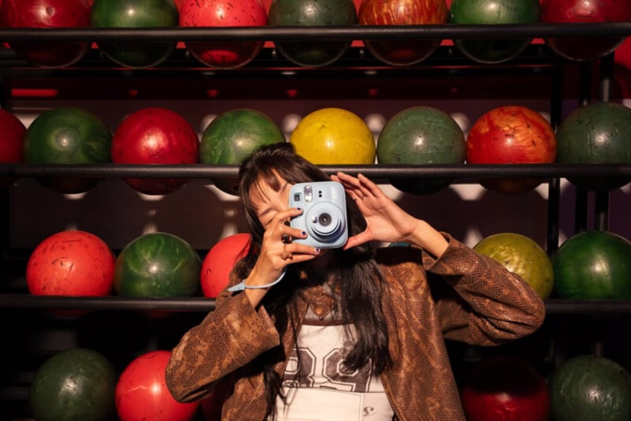 Person using the Fujifilm Instax Mini 13 in Frost Blue at a bowling alley