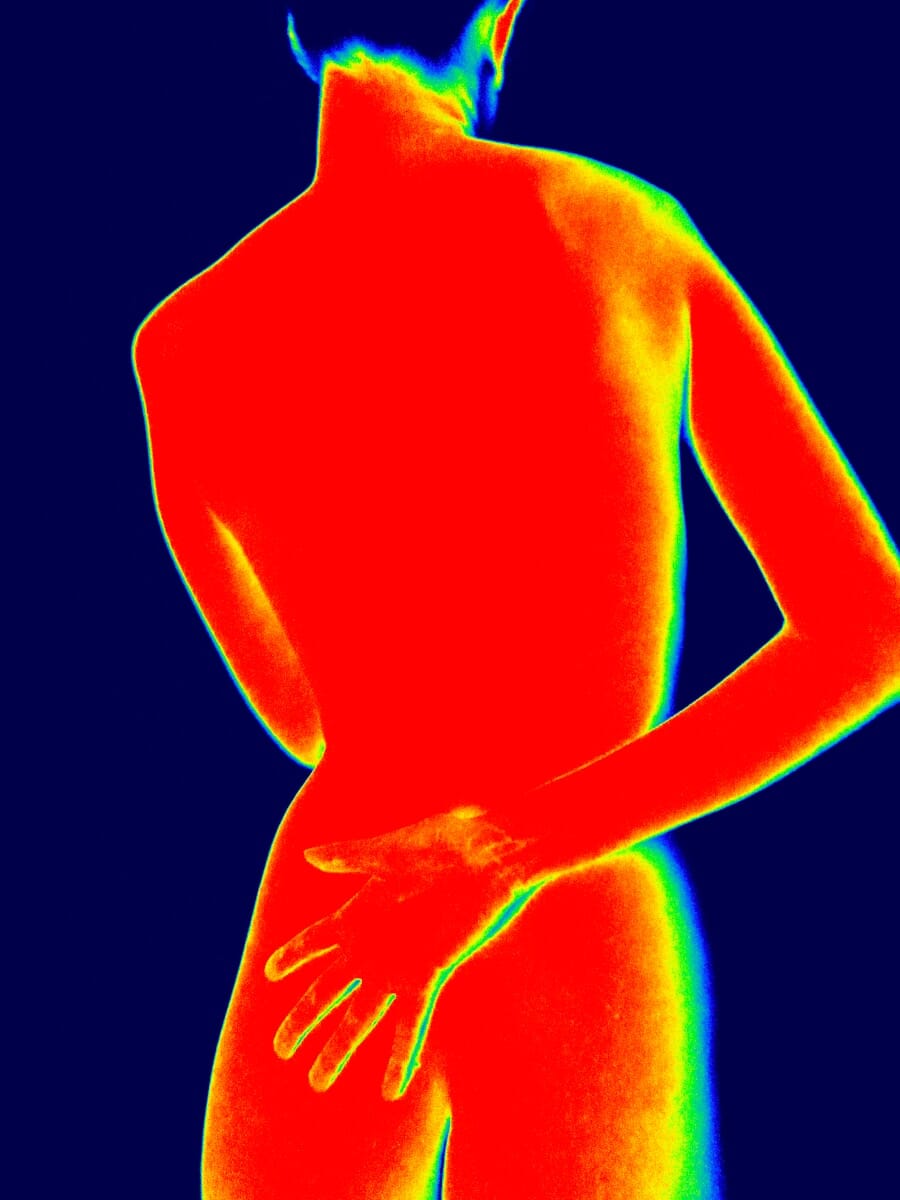 Thermographic view of a person showing heat signatures in red and yellow against a cool blue background