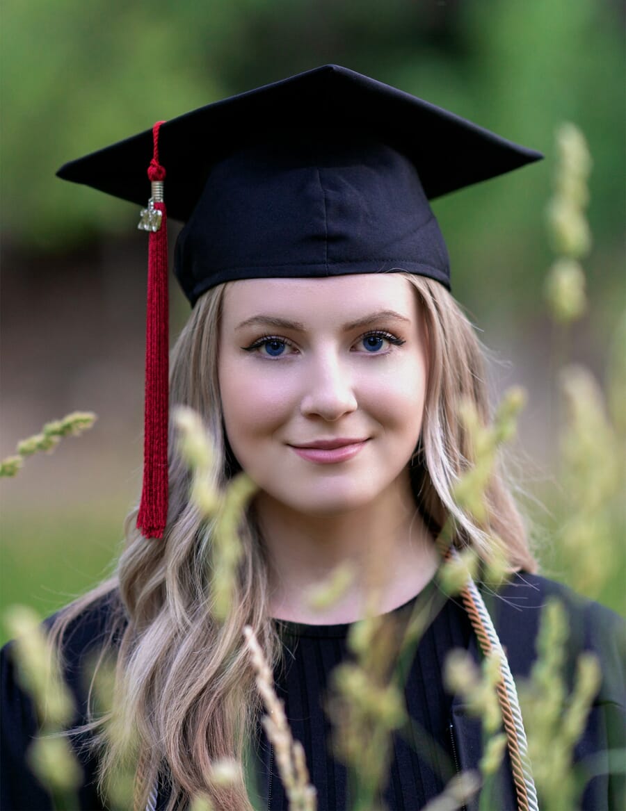 A graduate in cap and gown photographed in soft natural light