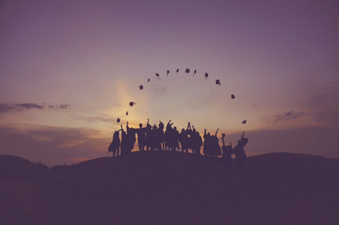 Graduates throwing their caps in the air silhouetted against a sunset