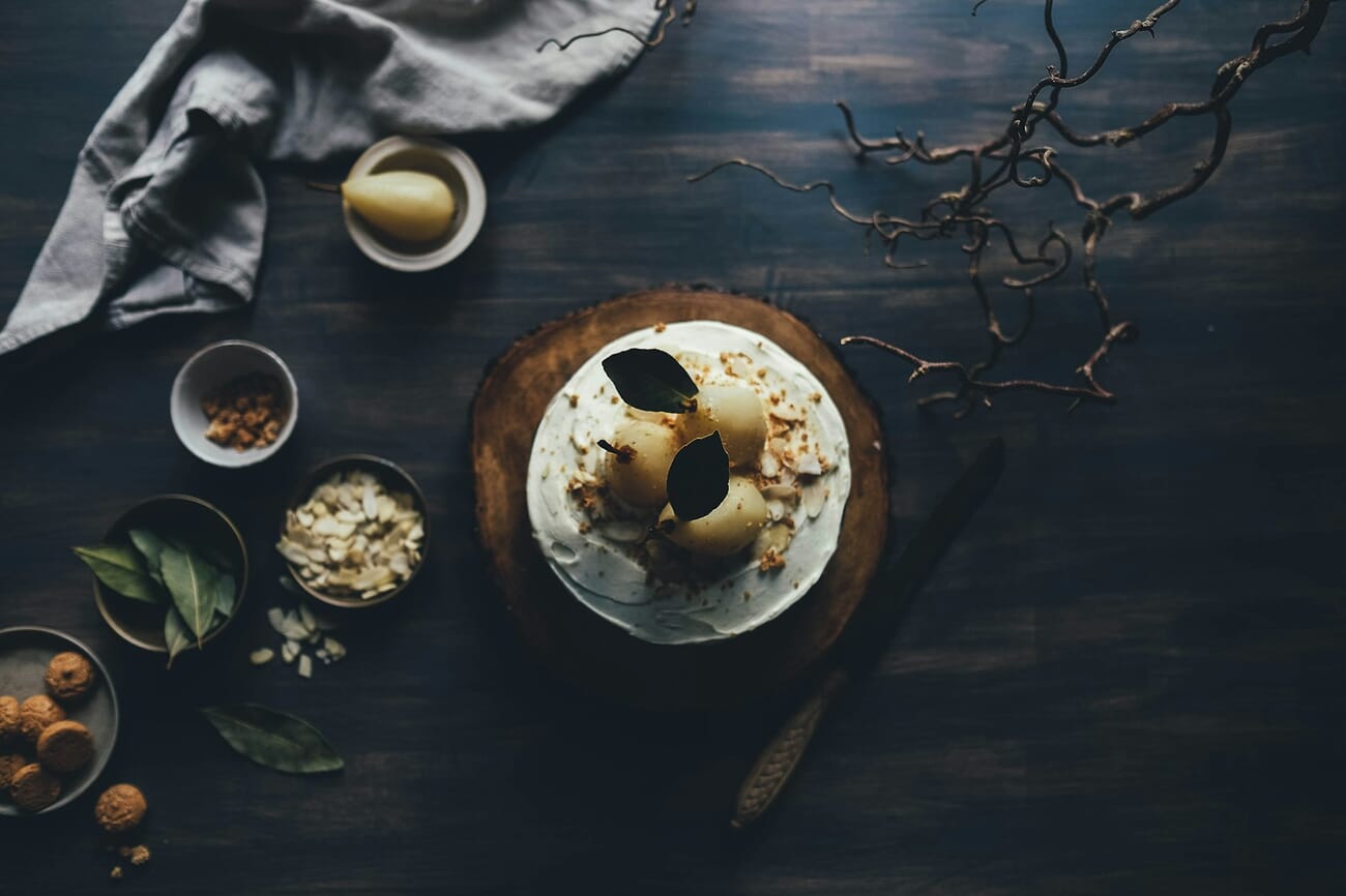 Dark moody still life of a cake with pears in low key lighting demonstrating dramatic shadow technique