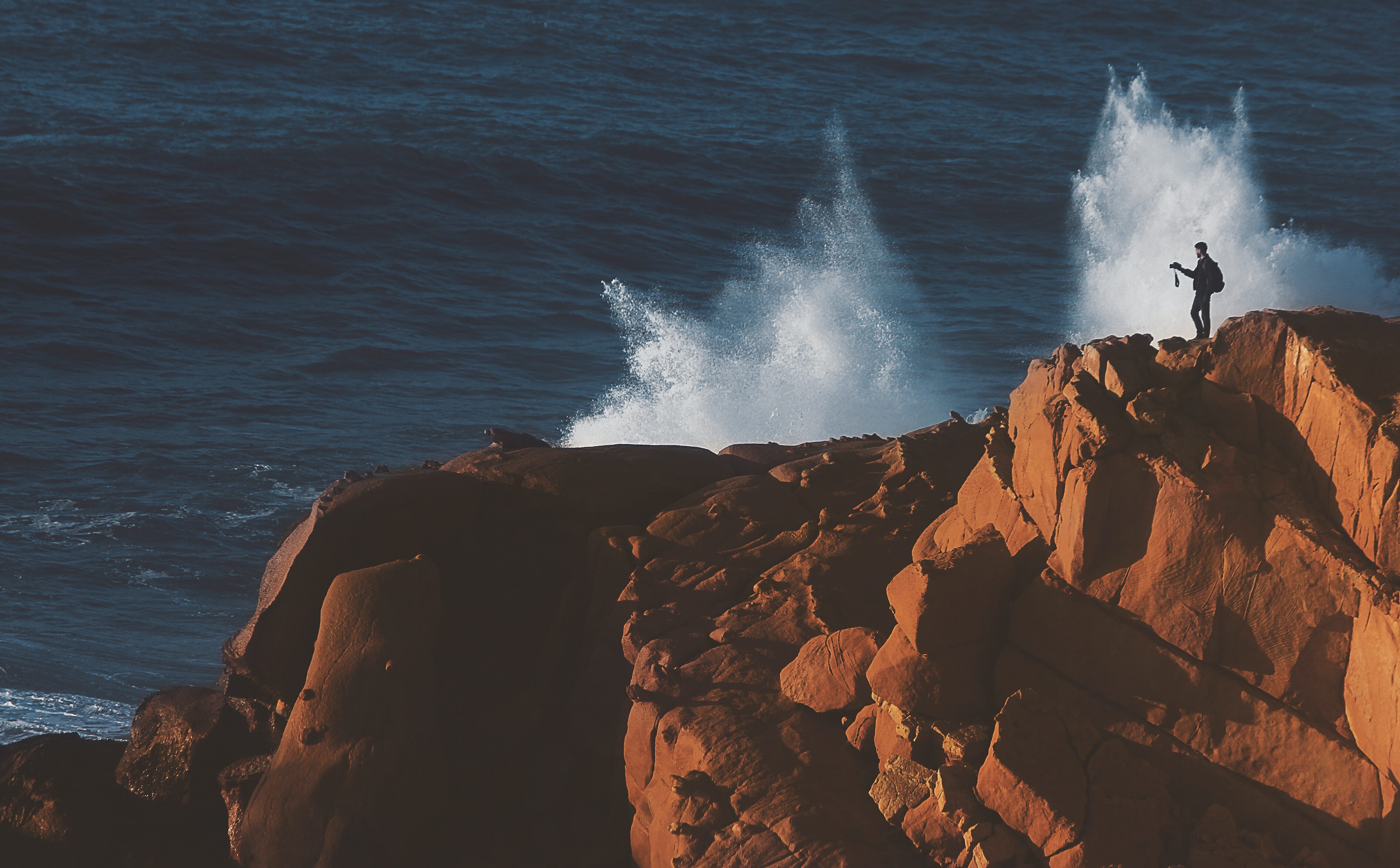 photographer by the ocean with sea spray