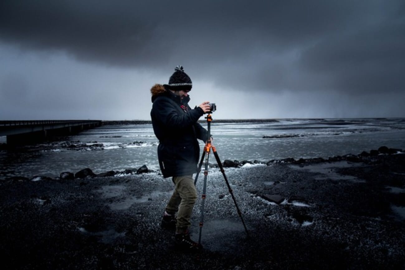 Photographer using a tripod to capture a seascape at sunset