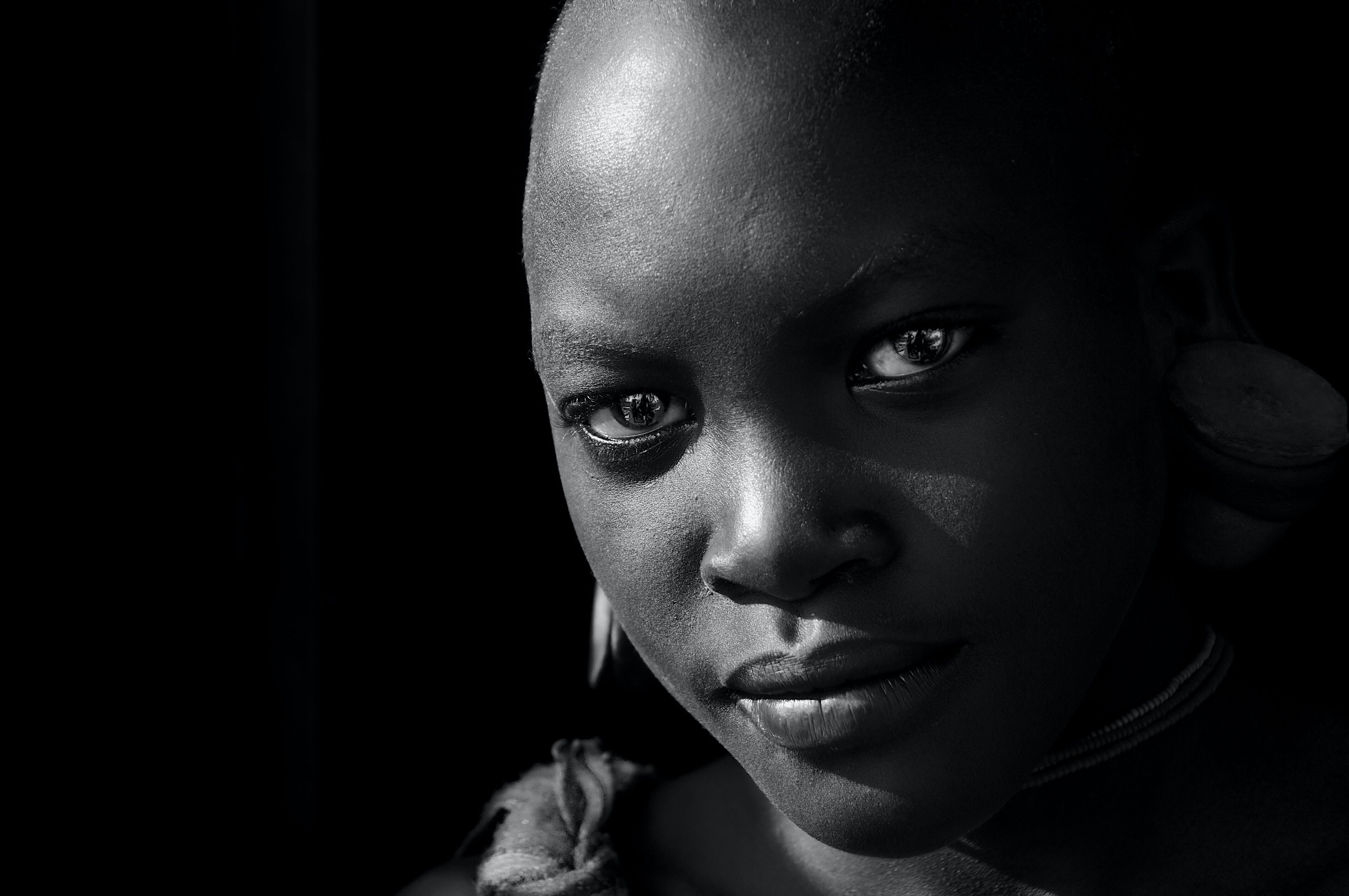 Close-up of a bald woman with shadowy features in black and white.