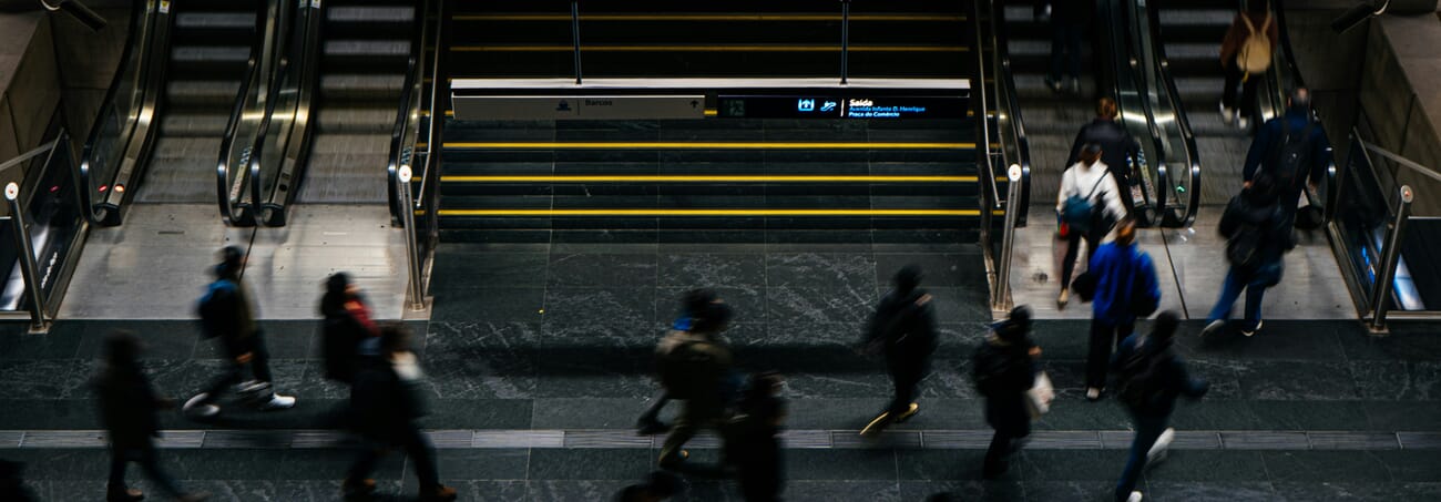 Motion blur of a moving crowd in a sharp-architecture atrium — clear demonstration of subject motion blur