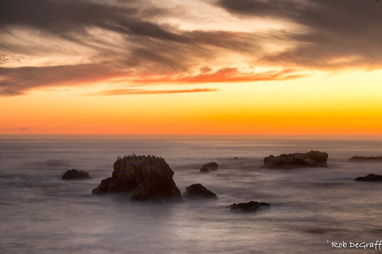 Shell Beach at dusk: orange horizon over tranquil sea with silhouetted sea stacks