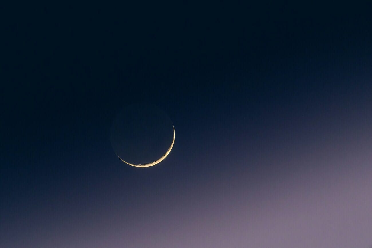 Crescent moon in a dark gradient sky photographed with a telephoto lens