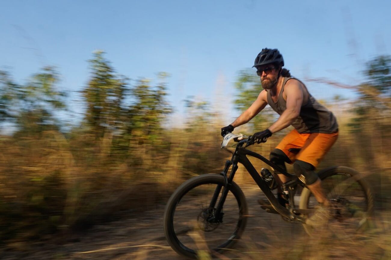 A mountain biker stays sharp while the forest behind streaks into motion blur during a panning shot