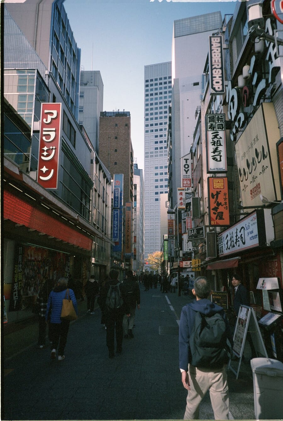 Bustling Tokyo street with colorful storefronts — shot on Minolta TC-1
