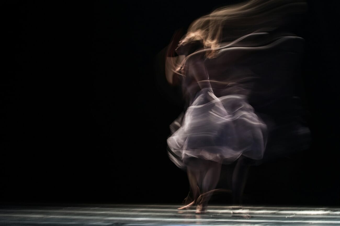 Dancer captured with motion blur — slow shutter speed creates ghostly streaks of movement