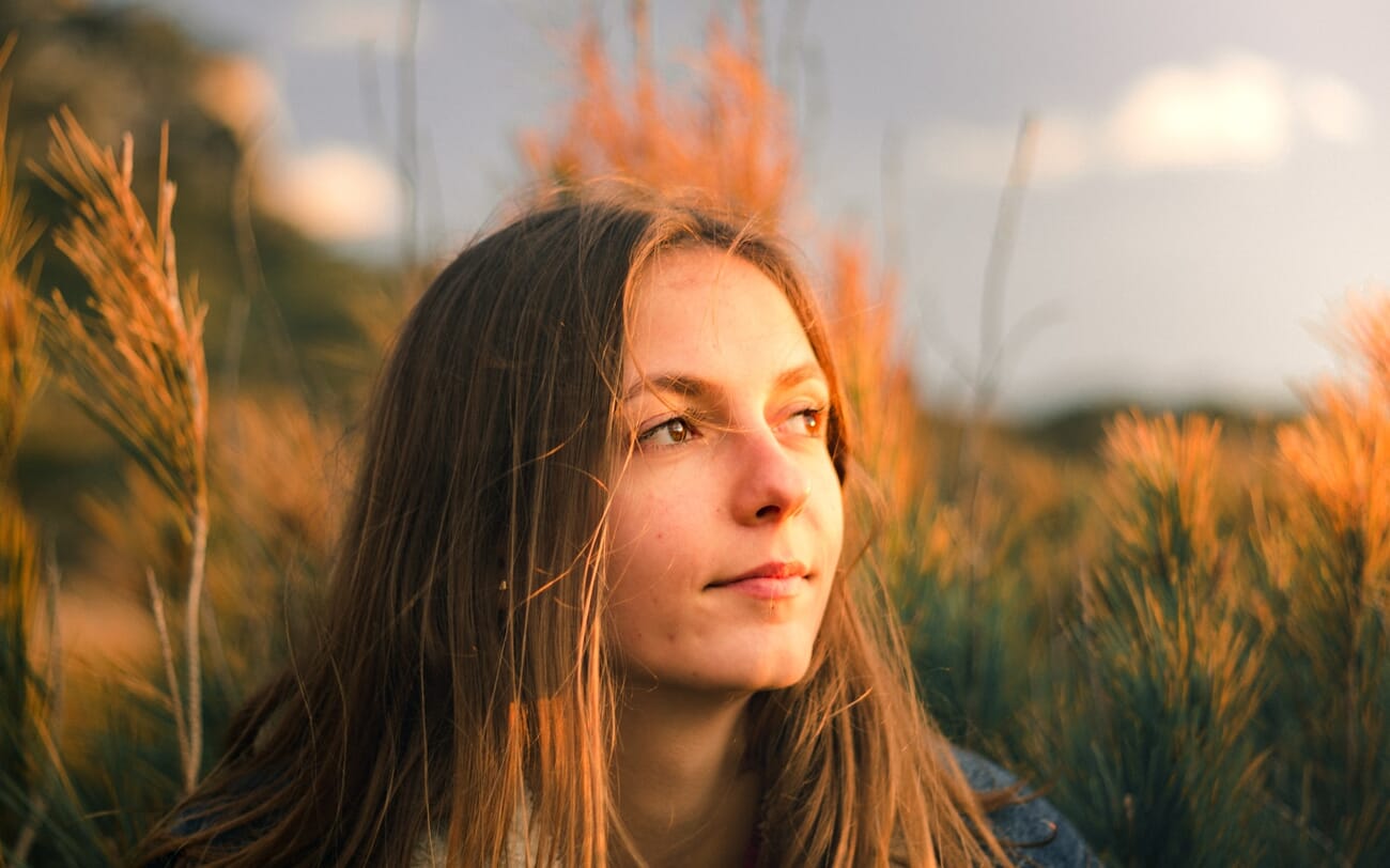Young woman backlit during golden hour in a field of tall grass