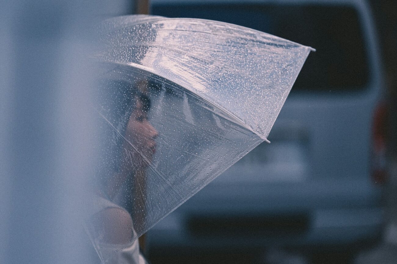 Woman holding a clear umbrella during a rain portrait session