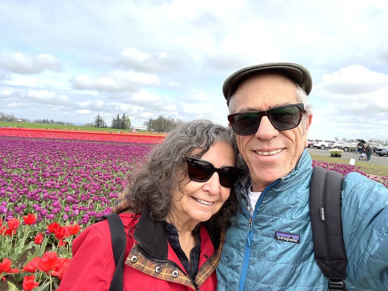 Couple posing among rows of red tulips in a flower field