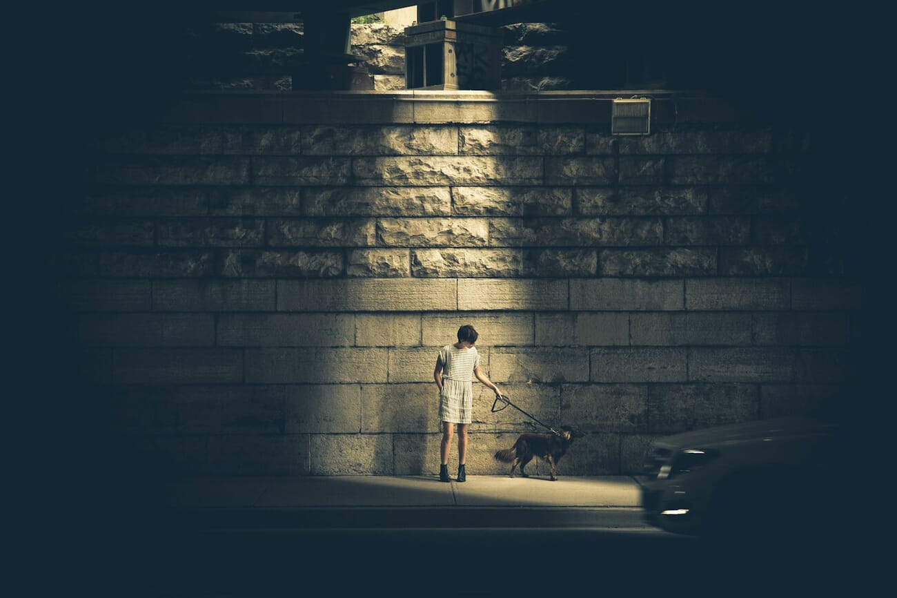 Street photography scene at night with a solitary figure walking through an urban setting with strong leading lines