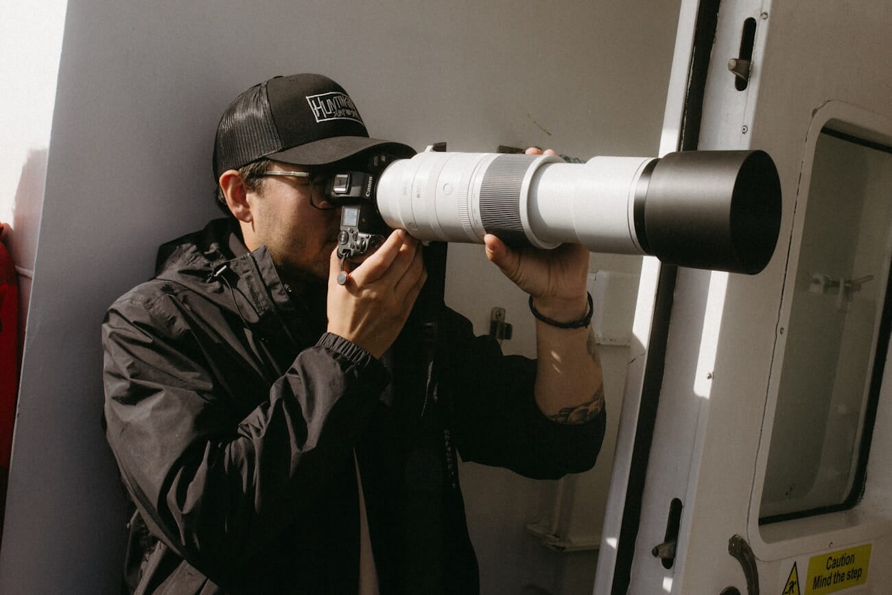 Photographer aiming a camera with a large telephoto lens