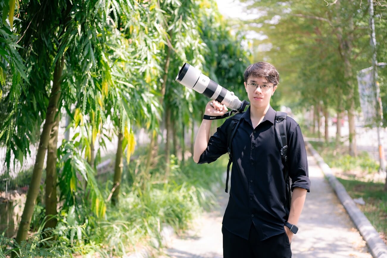 Photographer holding a Sony telephoto zoom lens