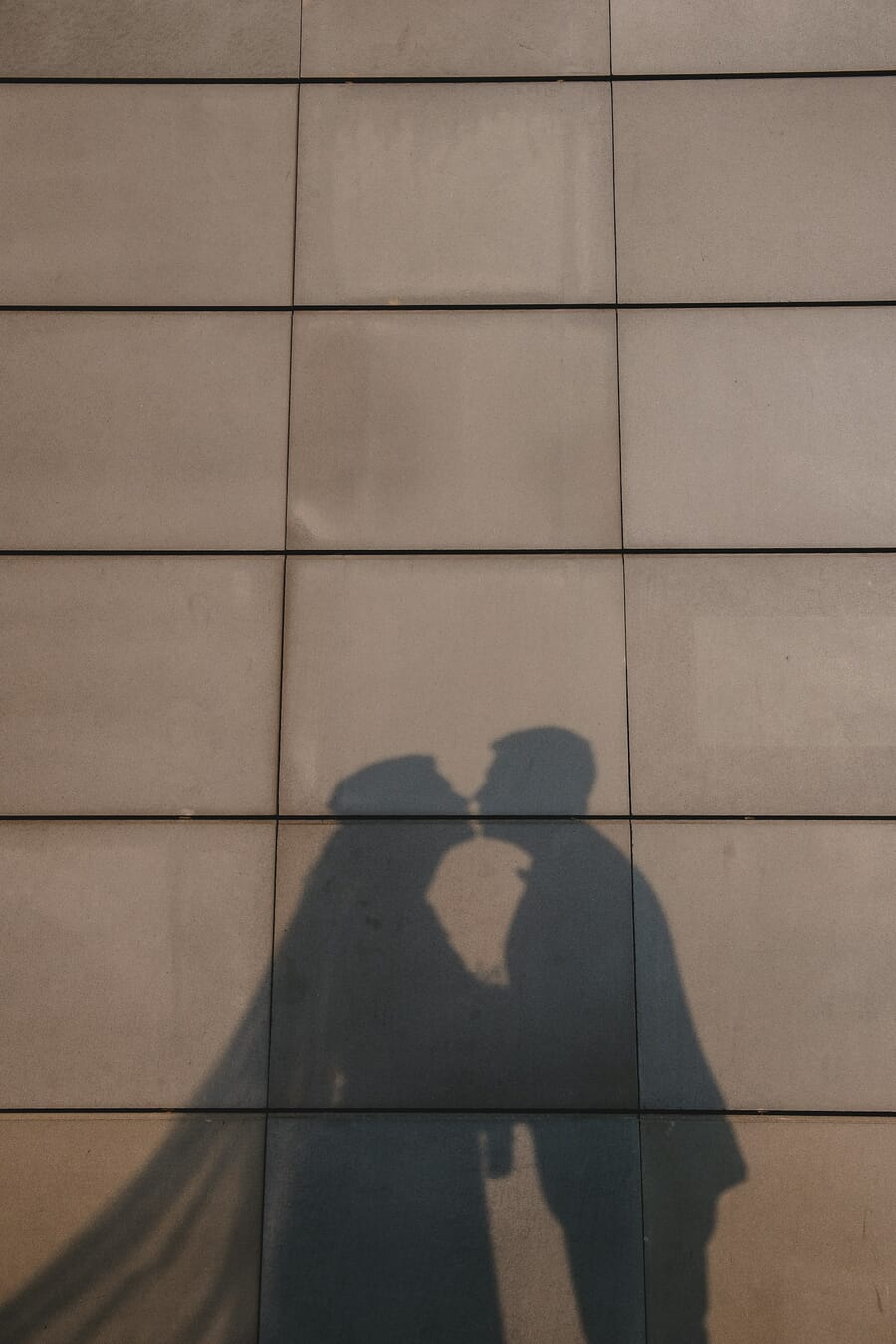 Shadow silhouette of two people kissing cast on a textured stone wall