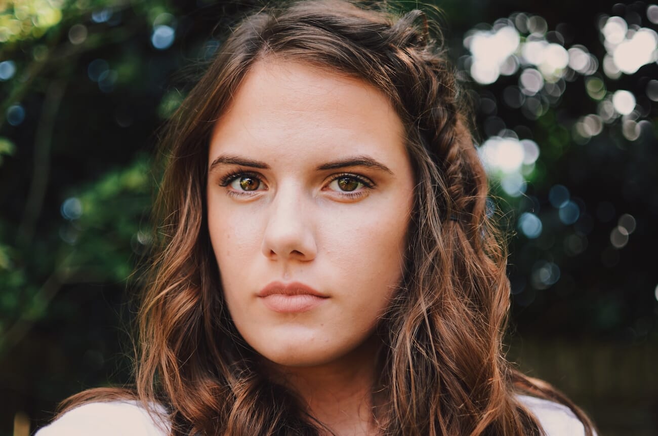 A portrait shot in natural window light, the subject sharply in focus against a softly defocused background, shot at f/2.0 · 1/320 · ISO 100
