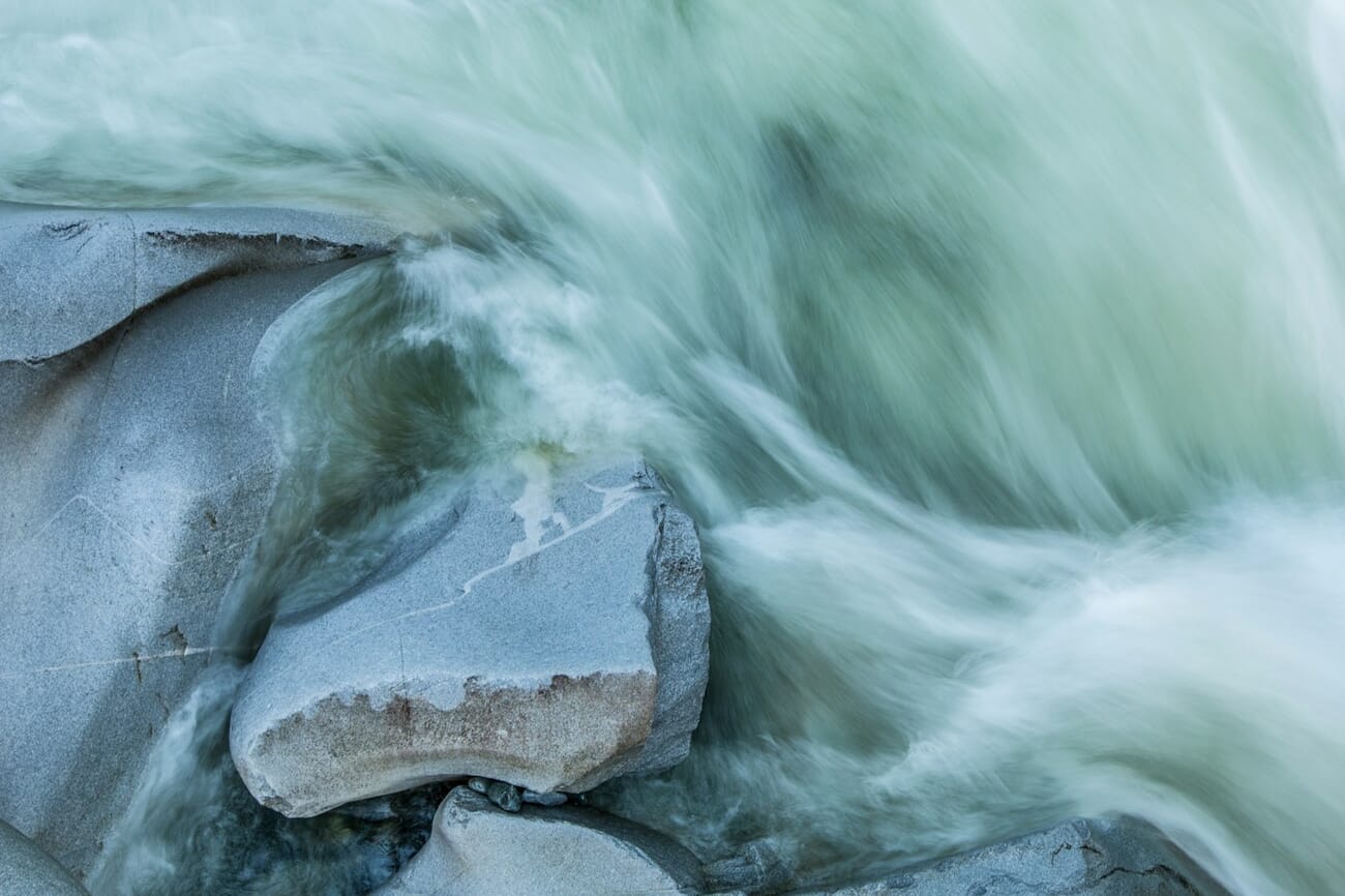 A riverbed cascading over rocks, water rendered as creamy motion blur by a long exposure, shot at f/11.0 · 1/5 · ISO 100
