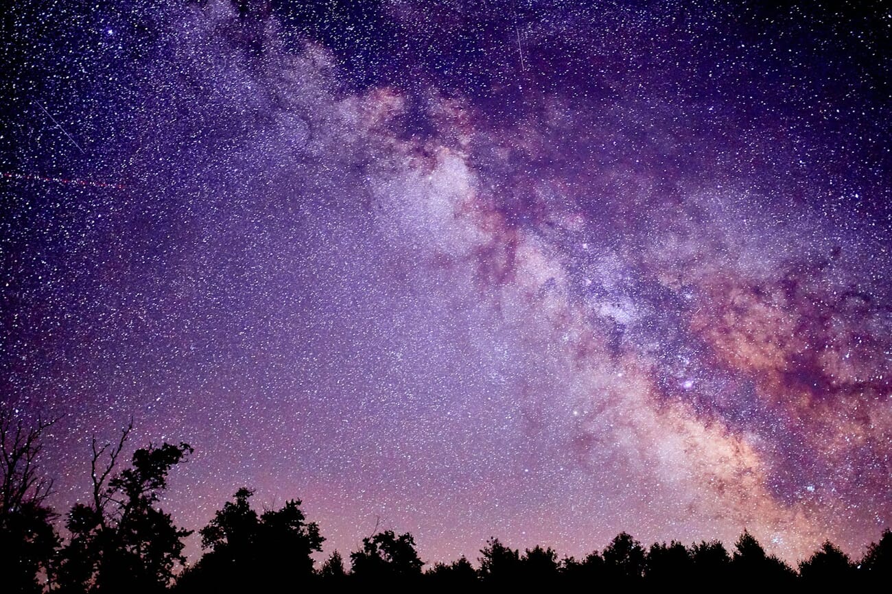 A starry night sky over an open landscape, captured with a wide-aperture prime and a long exposure, shot at f/1.4 · 15s · ISO 3200