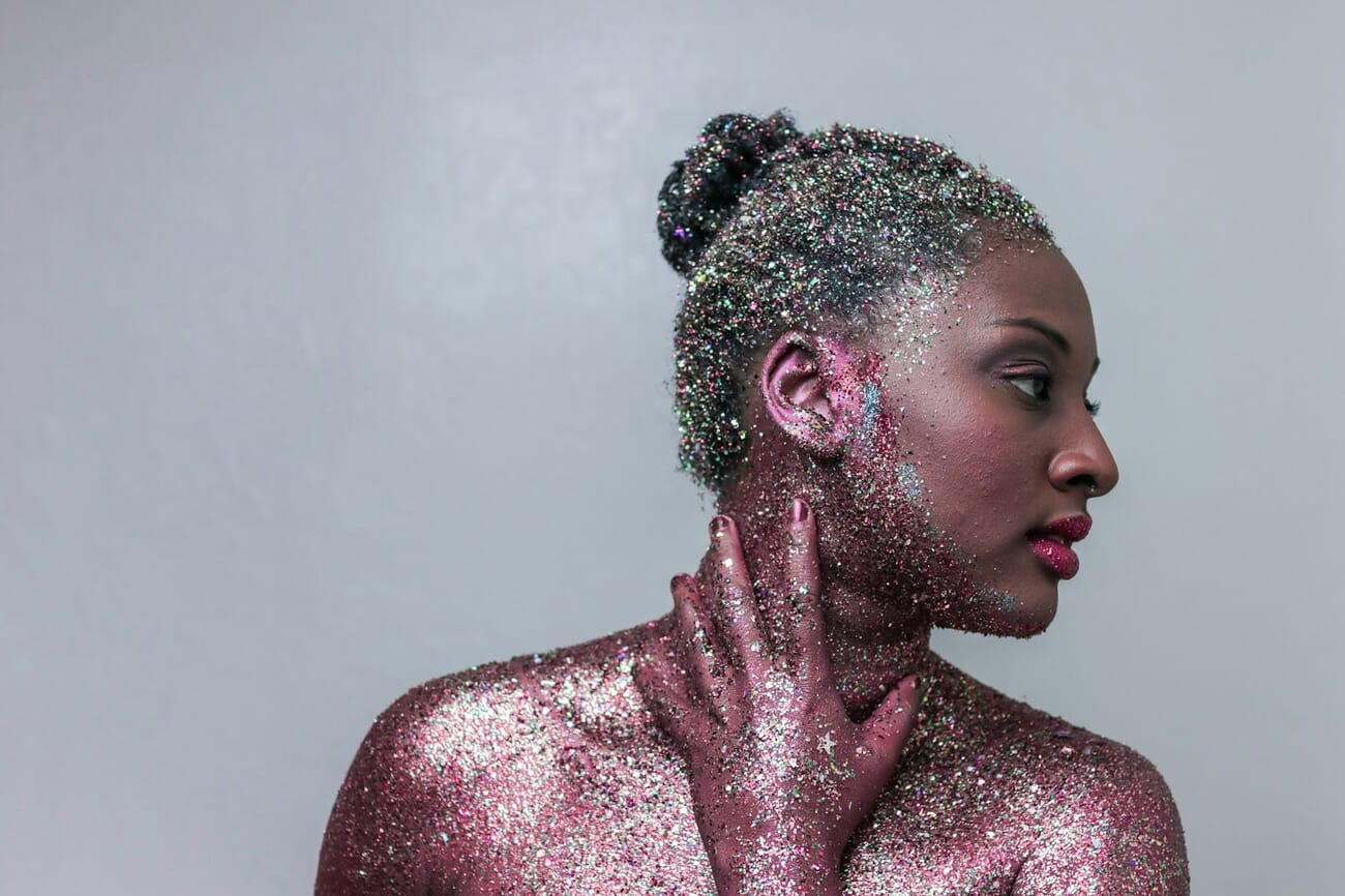 Creative portrait of a woman covered in pink and silver glitter under studio lighting