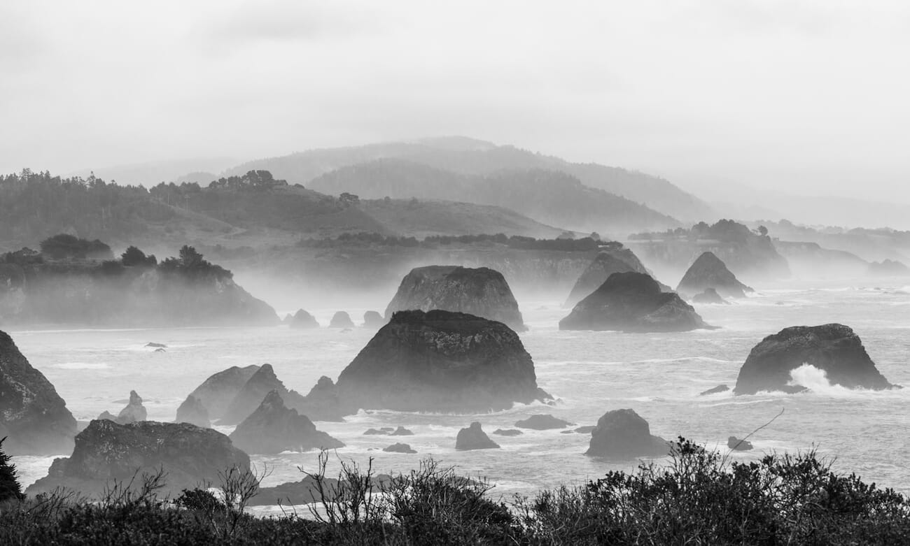 Misty ocean with rock formations and distant hills