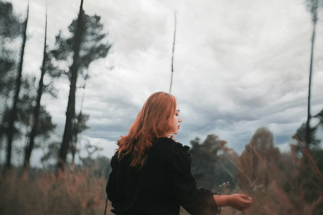 Environmental portrait of a woman standing in a field of tall grass shot on Fujifilm X-T10