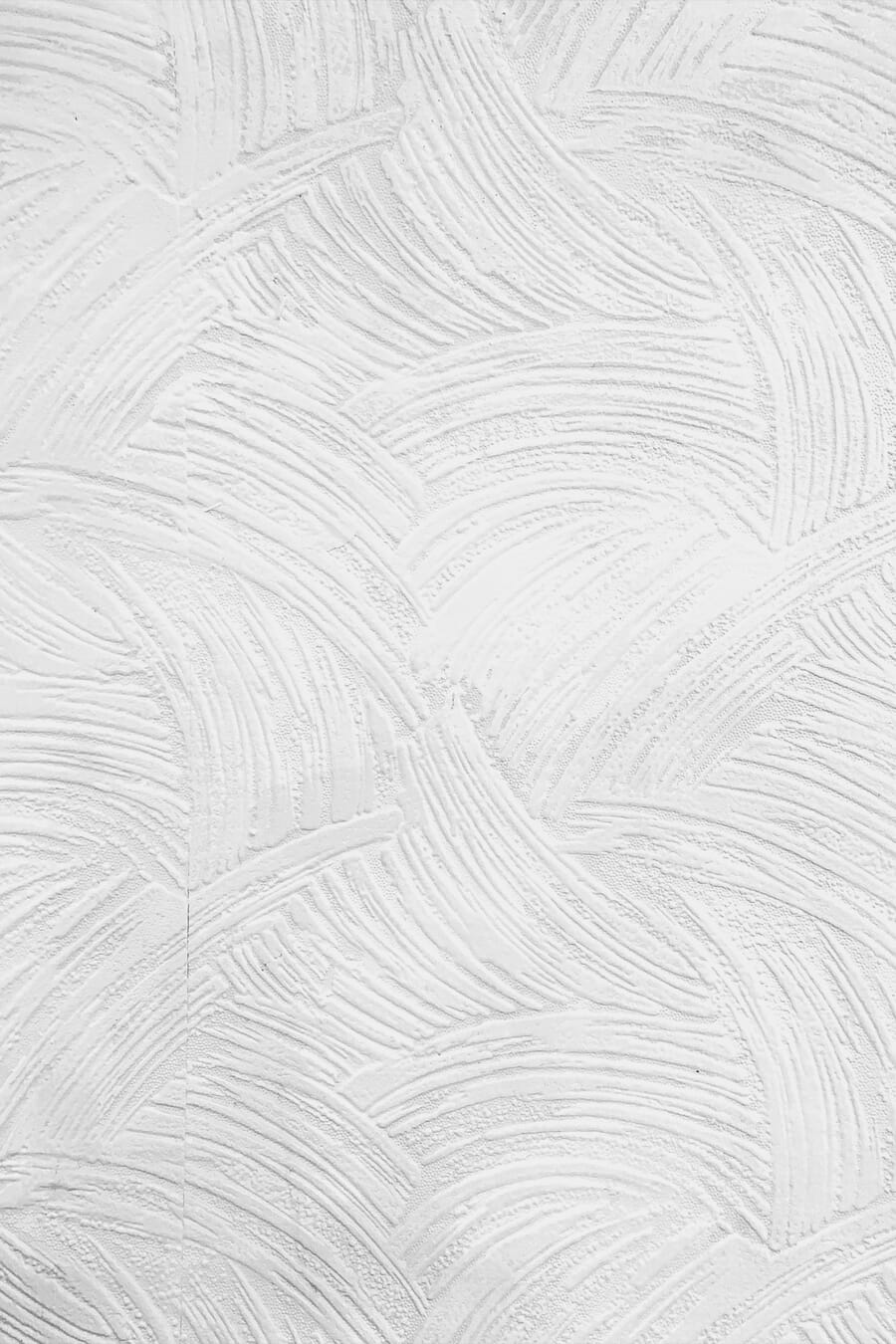 White wall with sweeping circular plaster strokes creating abstract texture