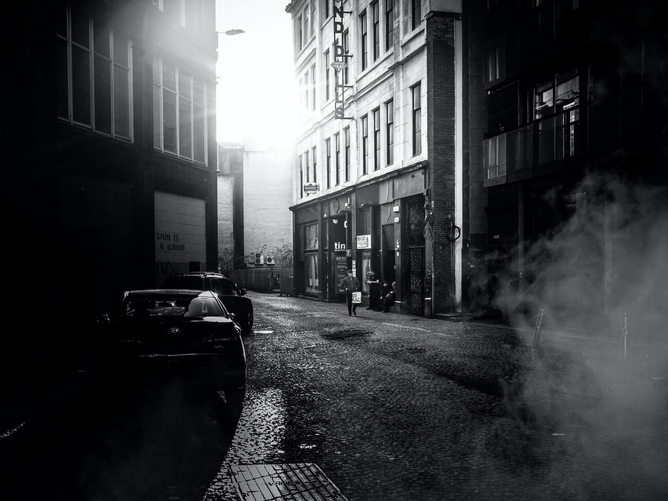 Moody black-and-white city street with steam and atmospheric texture