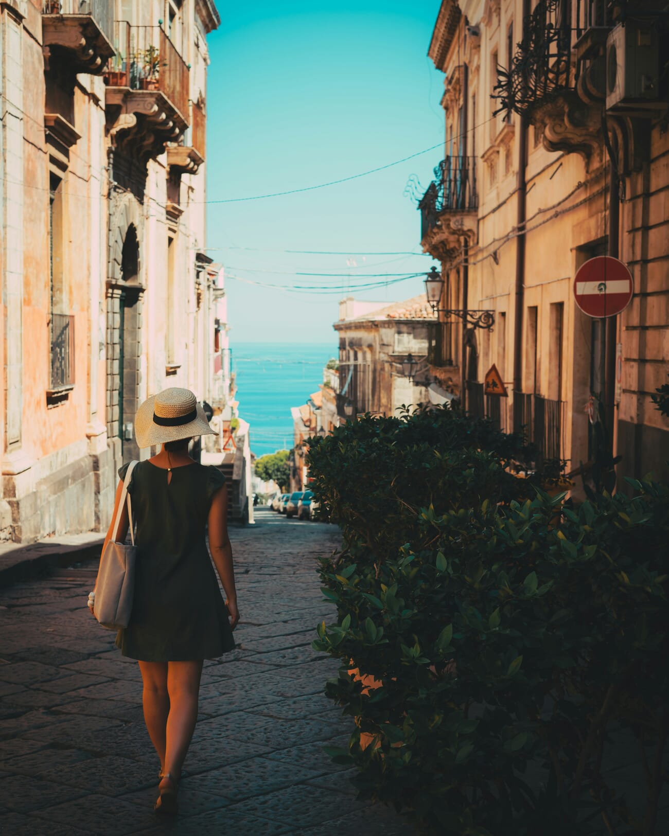 Woman walking down a sunlit cobblestone street — candid street photography example
