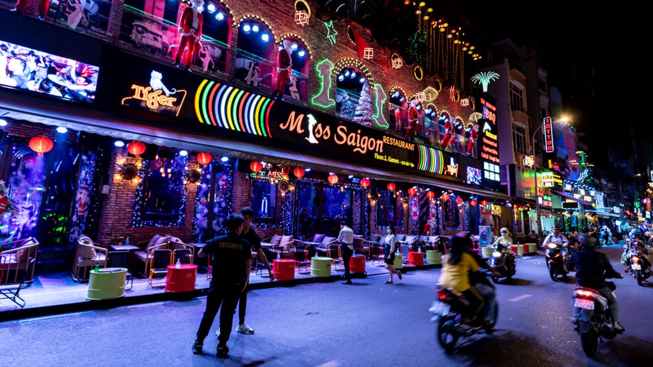 Neon signs lighting up a busy street in Saigon at night